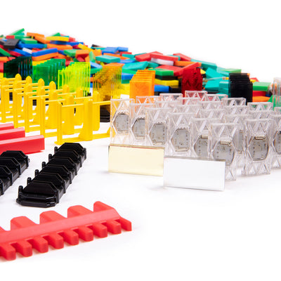 Atwood Toys Bulk Dominoes Super Mega Kit close-up of clear Electro Dominoes with bonus gold and silver dominoes, yellow spinners, red template, and multi-color domino pile